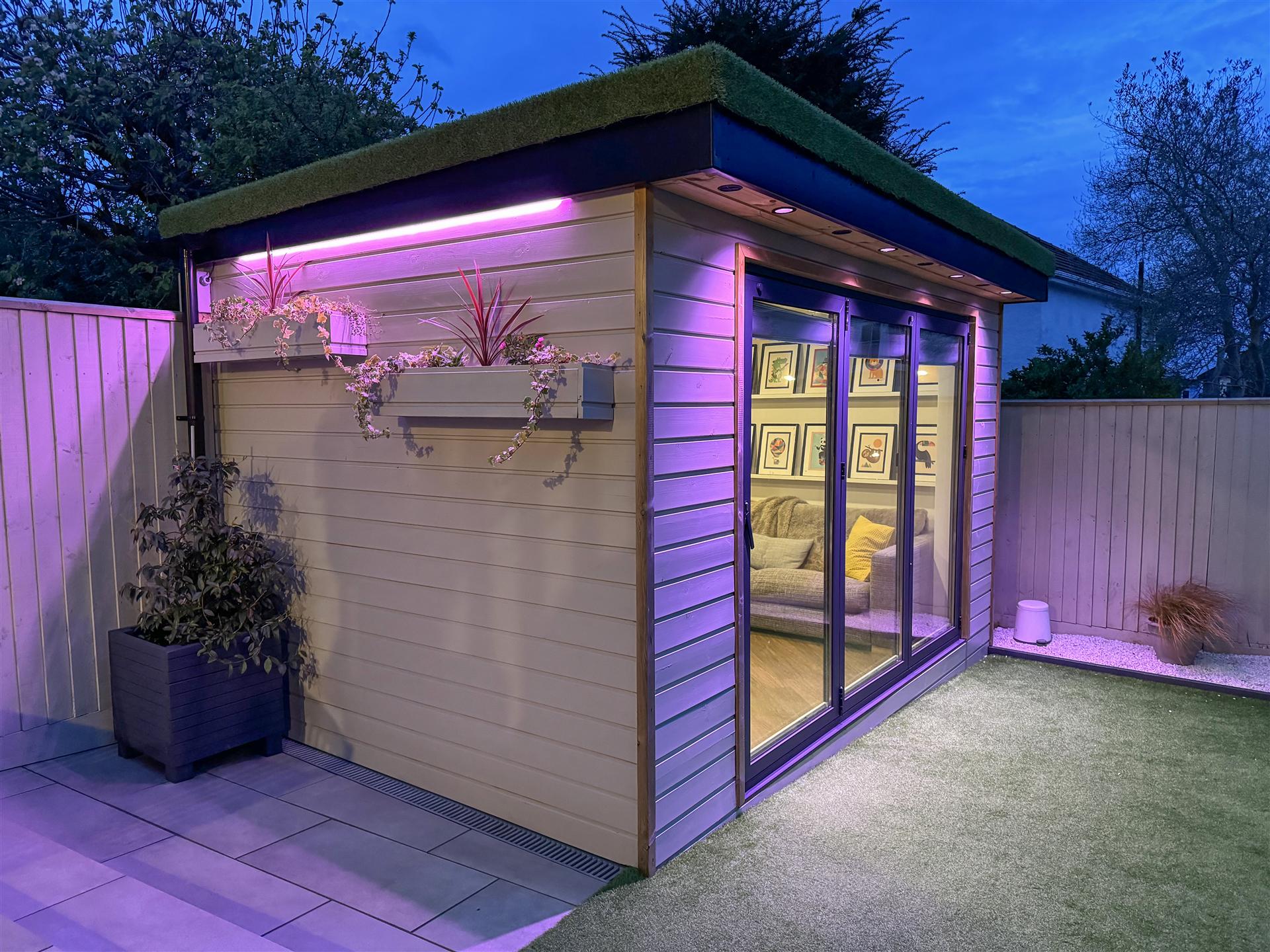 Garden studio at dusk with living green roof and accent lighting by Nest