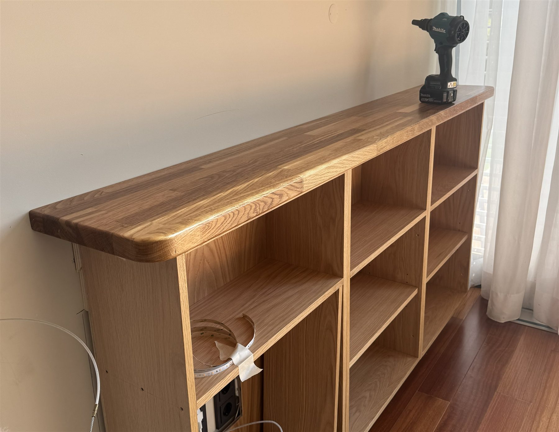 A bespoke oak unit being fitted on site, drill and LED strip mid-installation